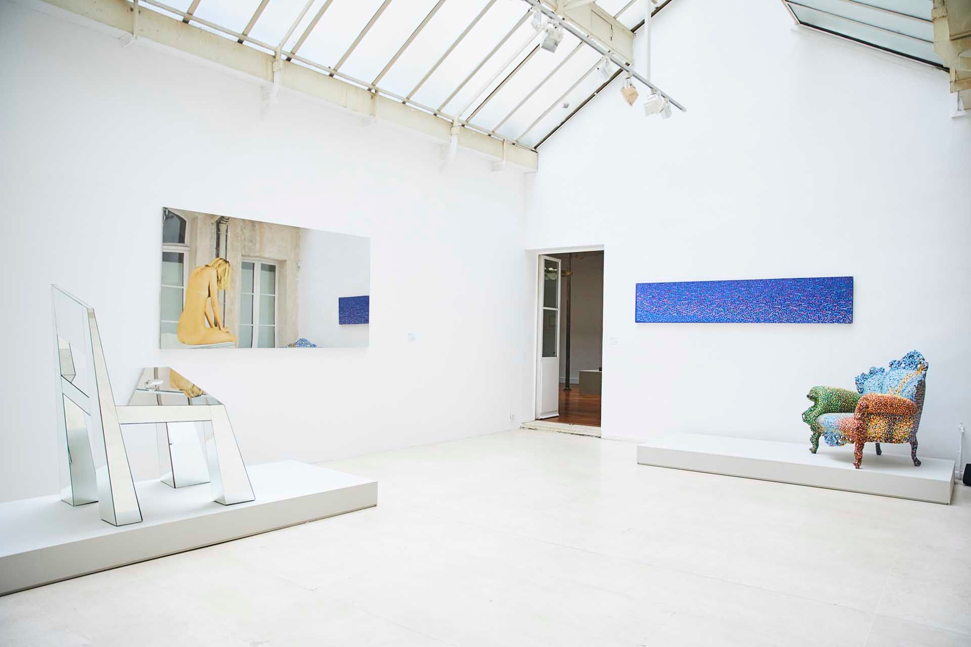 White gallery with skylights and blue paintings