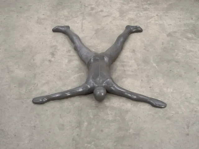 Dark sculptural figure against a concrete wall