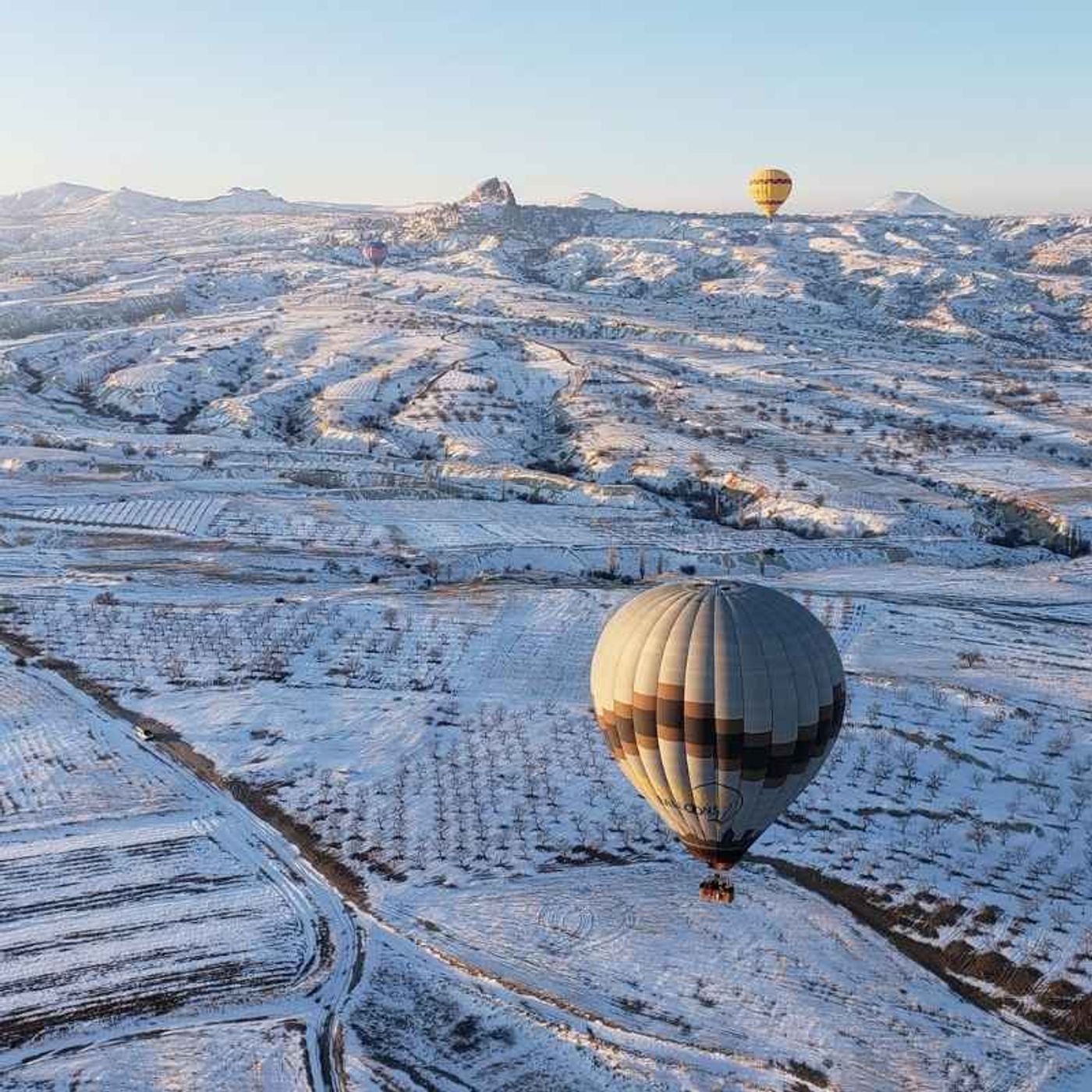 Aerial view of Cappadocia, Turkey covered with snow and hot air balloon flying over