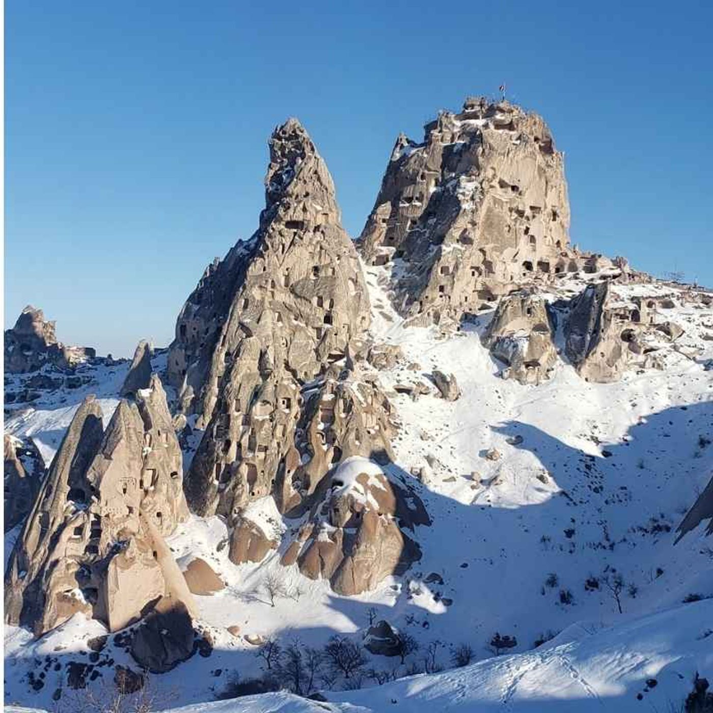 Cappadocia's rock formations during winter with snow and blue sky