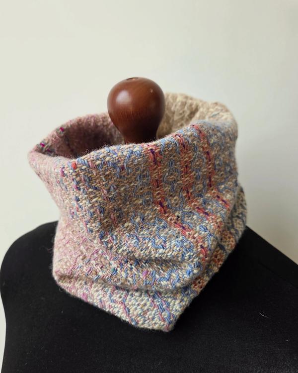 Handwoven merino wool cowl in pastel shades of pink, blue, beige and cream with a multicoloured geometric pattern