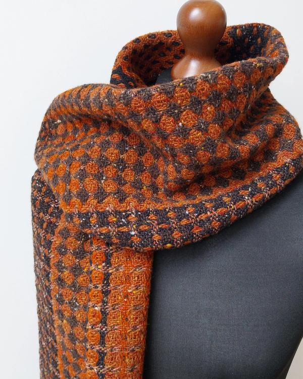 Softly draped handwoven Donegal wool shawl featuring a bold reversible geometric pattern in rust and dark brown, highlighting the dimensional woven texture