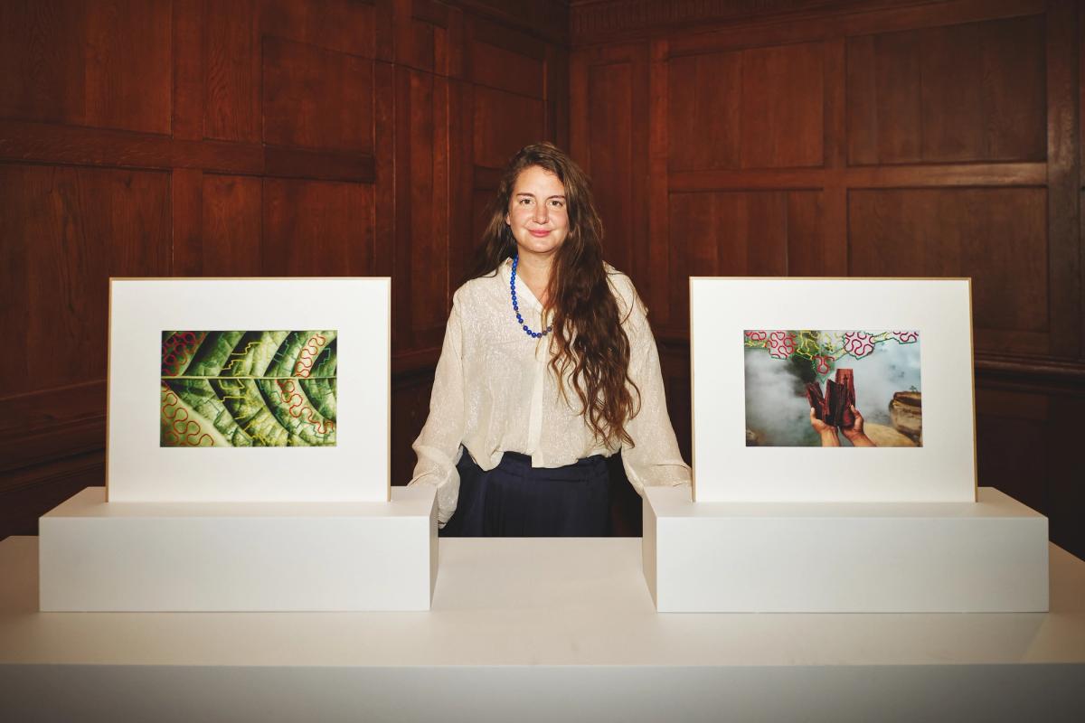 La photographe Ana Elisa Sotelo entre deux photographies de la série Portraits of the Multiverse, lors de la soirée de remise du Thinking Sustainability* Photography Prize (*Penser le développement durable) de la Fondation Louis Roederer, le 7 novembre 2024 au Reid Hall, à Paris. © Alexis Anice