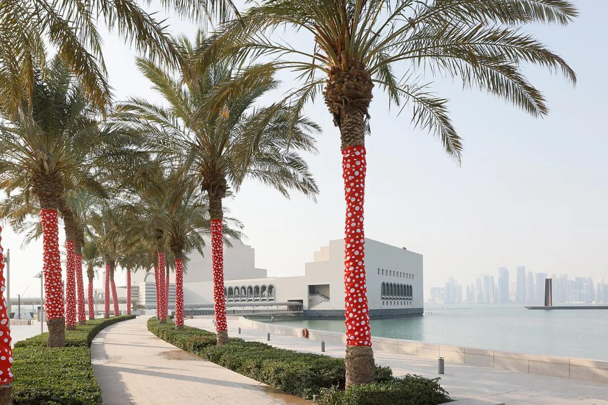 Yayoi Kusama, Ascension of Polka Dots on the Trees (2002/2022), vue de l'installation. Au fond, le Musée d'art islamique de Doha, au Qatar. Photo : Iwan Baan. © Yayoi Kusama. Courtesy David Zwirner, Ota Fine Arts et Victoria Miro