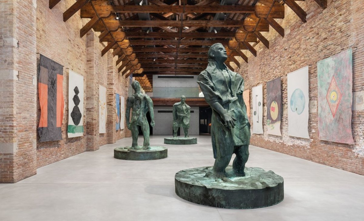 Vue de l’exposition «Thomas Schütte. Genealogies» avec, du premier au dernier plan : Mann im Wind II, I et III (bronze, 2018); aux murs : DEKA Fahnen (bannières peintes, 1989). © Thomas Schütte. Courtesy de Peter Freeman, Inc., New York, Paris et du Palazzo Grassi – Pinault Collection. Photo Marco Cappelletti