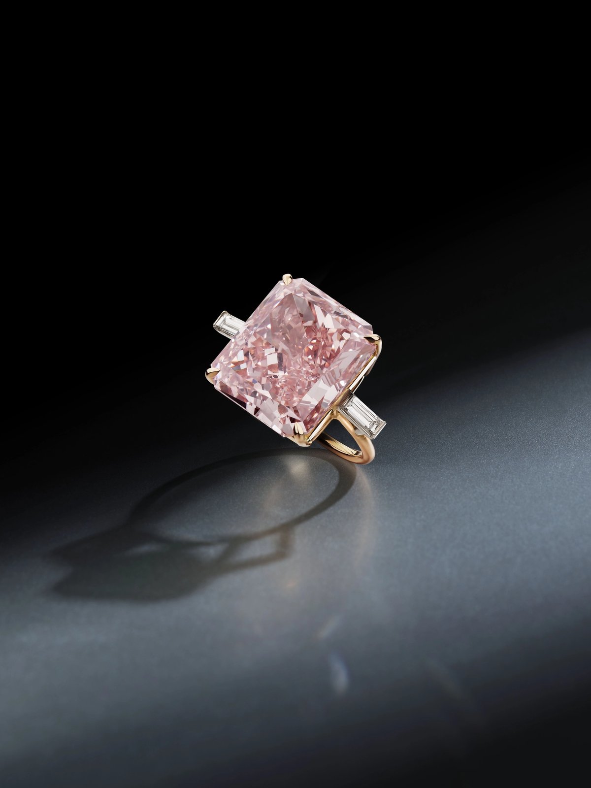 Bague en diamant rose intense. Sertie d’un diamant rectangulaire modifié de taille brillant de couleur rose intense pesant 20,19 carats, rehaussé de diamants baguettes, taille 51. Est. 11-16,5 millions de dollars. © Phillips.