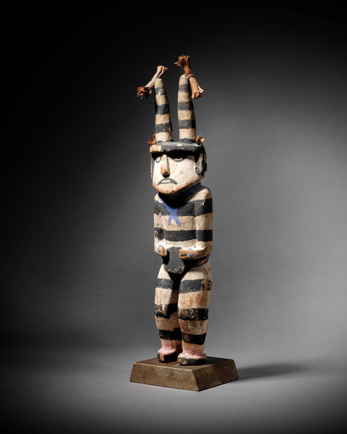 Clown Hano – Koshare Hopi, Arizona, H. 28,5 cm (sans le socle ni les fibres), bois sculpté (racine de cottonwood), pigments naturels, fibres végétales, années 1900.
Courtesy Giquello