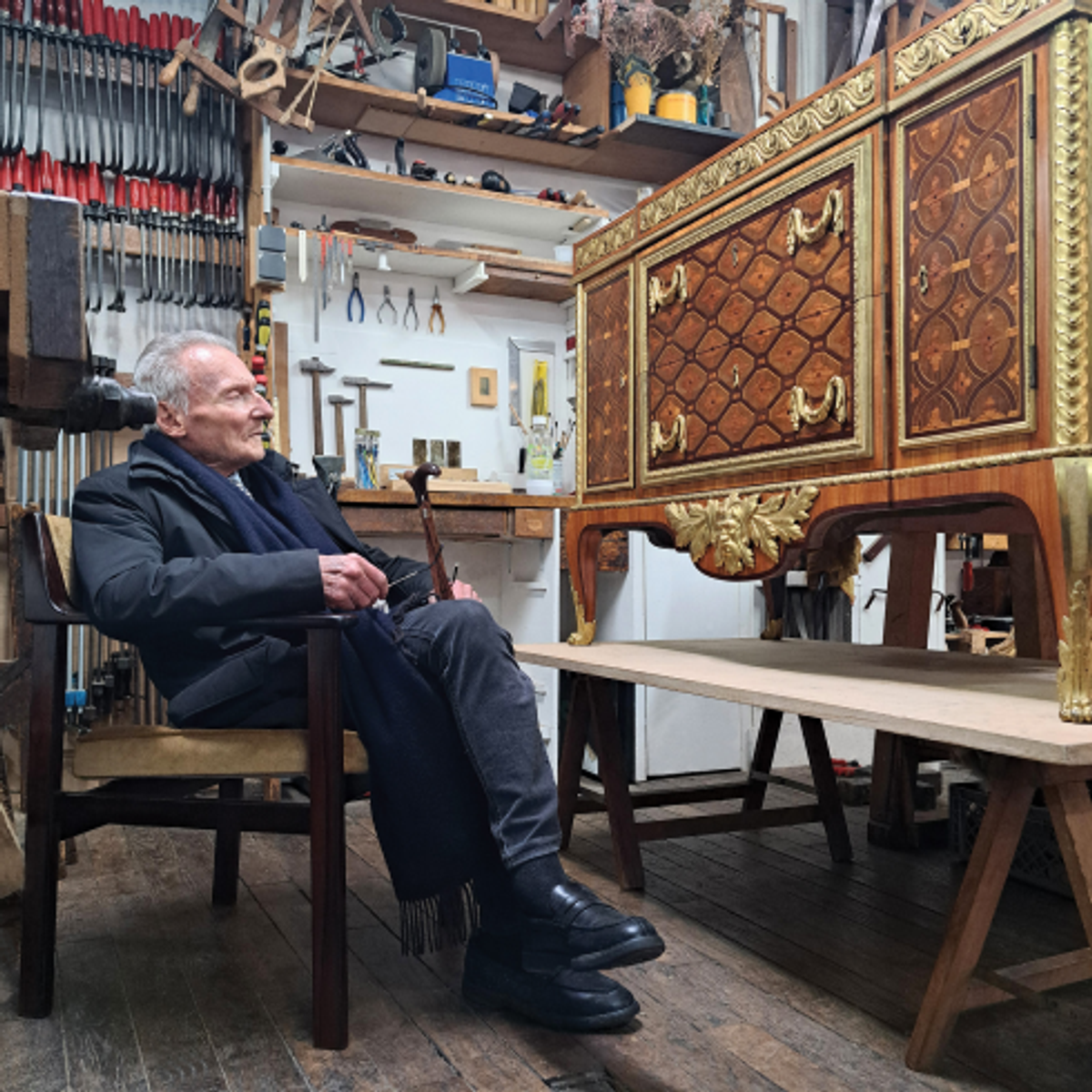Portrait de Daniel Alcouffe dans l’atelier d’ébénisterie Michel Jamet à Paris (géré depuis 2020 par Tristan Desforges) observant une commode Transition attribuée à Martin Carlin, provenant de la collection du comte de Buffon, intendant du cabinet d’histoire naturelle du Roi. Elle fut acquise par Bernard Steinitz dans les années 1990, puis revendue, avant d’être récemment rachetée par la maison Steinitz. Photo Tristan Desforges