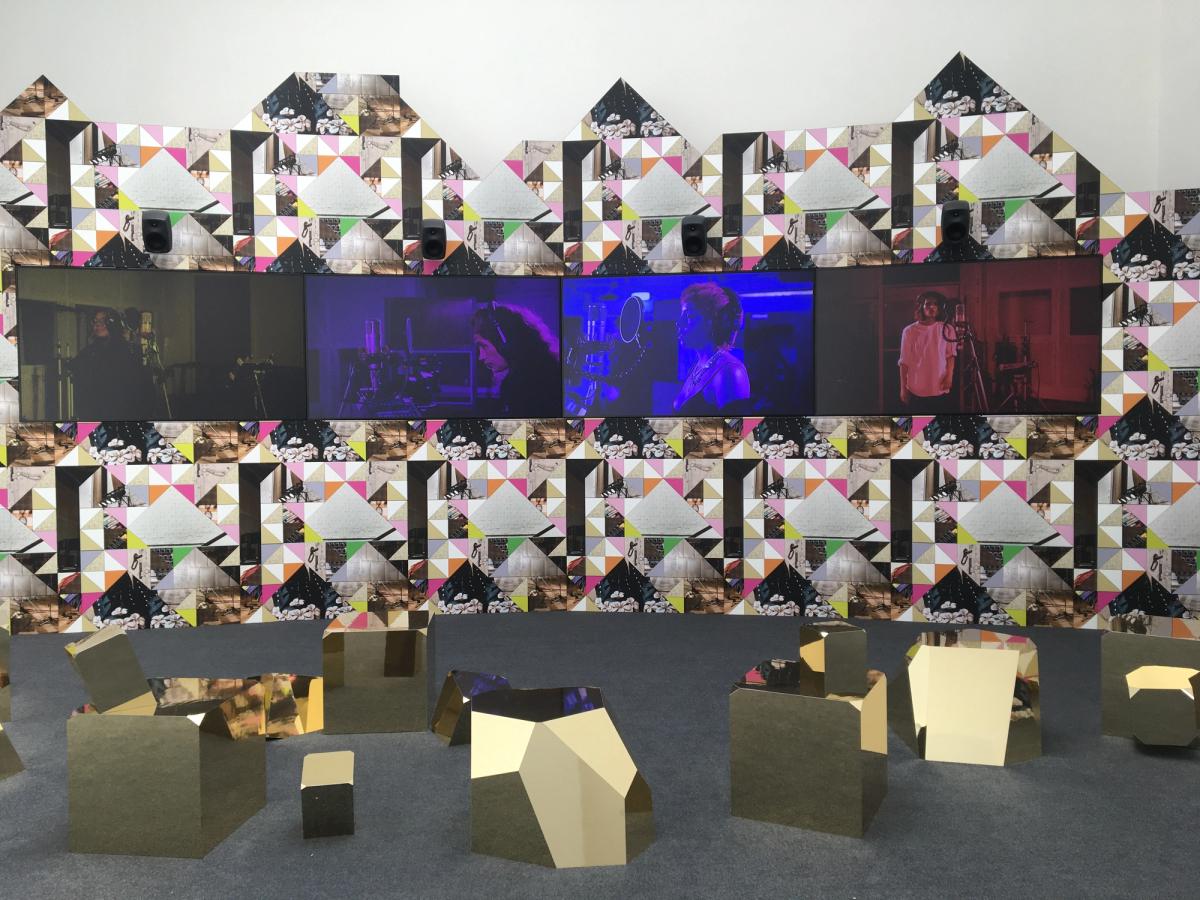 « Feeling Her Way » de Sonia Boyce présente dans le pavillon britannique un chœur de voix féminines noires dans une scénographie faisant la part belle au papier peint et à des structures géométriques en 3D dorées. Photo : Stéphane Renault