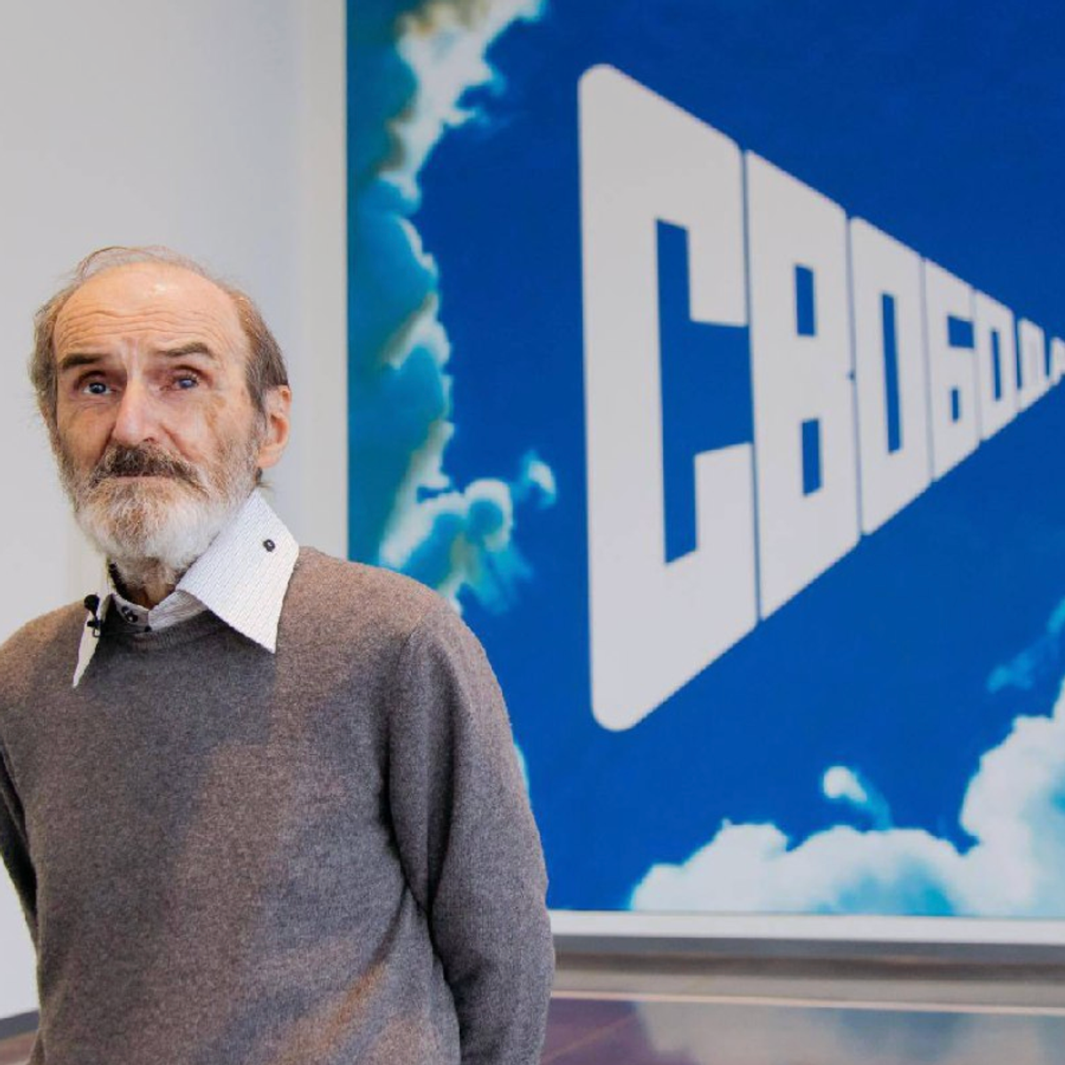 The Art Newspaper Russia a annoncé le décès de l’artiste en diffusant sur Telegram cette photo le montrant devant une de ses toiles offerte au Centre Eltsine d’Ekaterinbourg. Le mot svoboda (« liberté ») en cyrillique traverse en lettres capitales un ciel bleu dégagé. D.R.