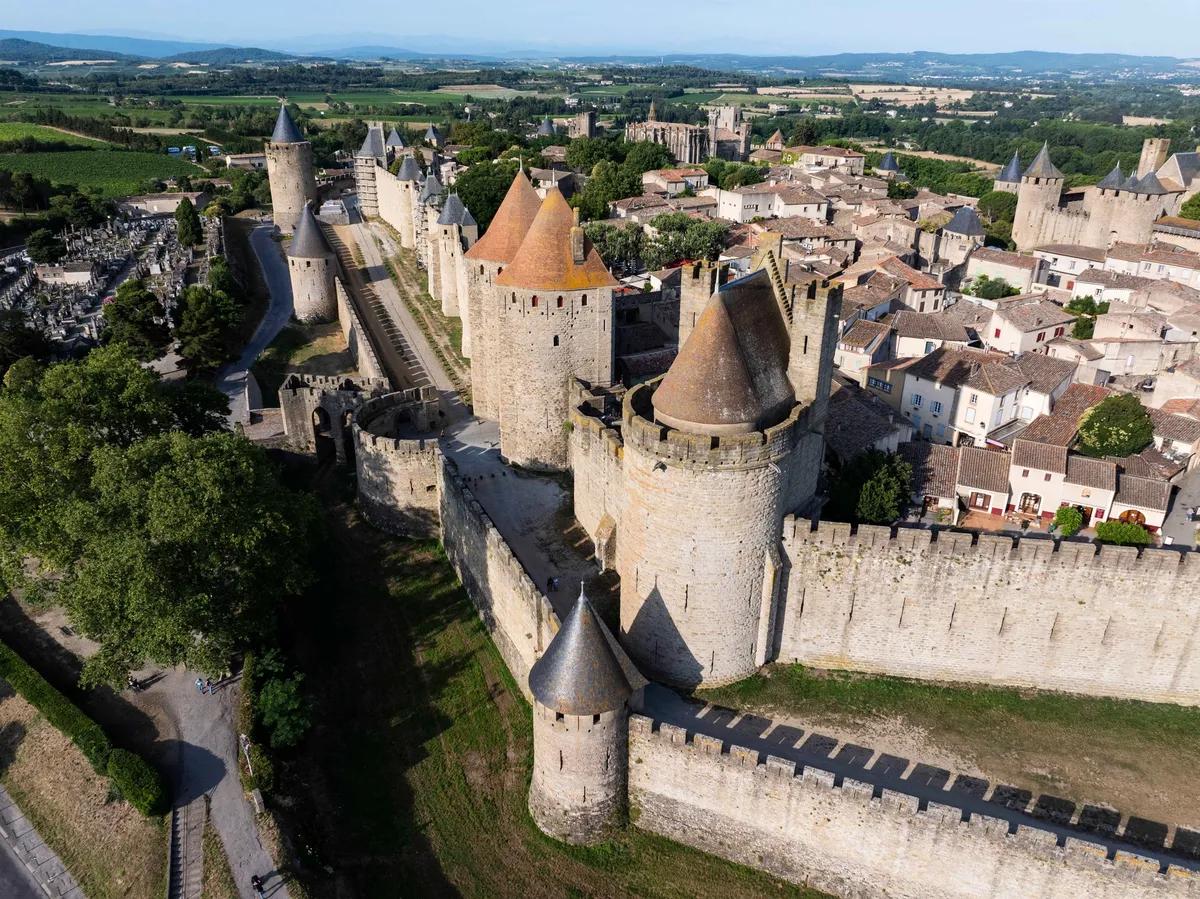 Vue aérienne de la cité médiévale de Carcassonne, dans le département de l’Aude. Grâce à un projet de restauration de l’enceinte et des tours de guet, les visiteurs peuvent désormais parcourir un circuit complet de 1,3 kilomètre sur les remparts supérieurs. © Sammy Billon – CMN