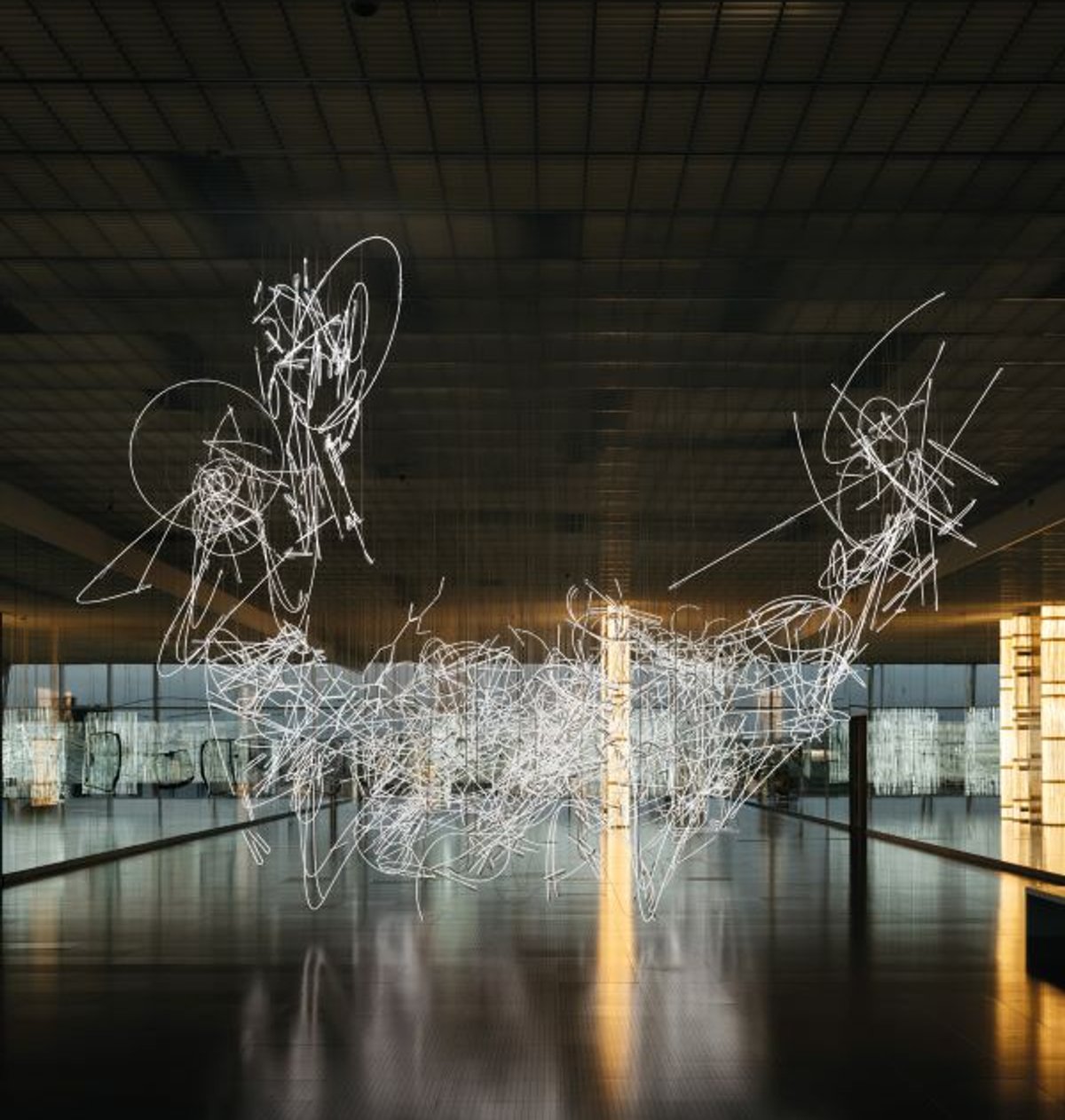 Vue de l’exposition « Cerith Wyn Evans. Lueurs empruntées » au Centre Pompidou-Metz, 2025 : au premier plan, Neon Forms (after Noh), 2015-2019, néon blanc ; à l’arrière-plan, Metz Drift, 2021, néon blanc. © Cerith Wyn Evans. Courtesy de White Cube et de Marian Goodman Gallery. Photo Lewis Ronald