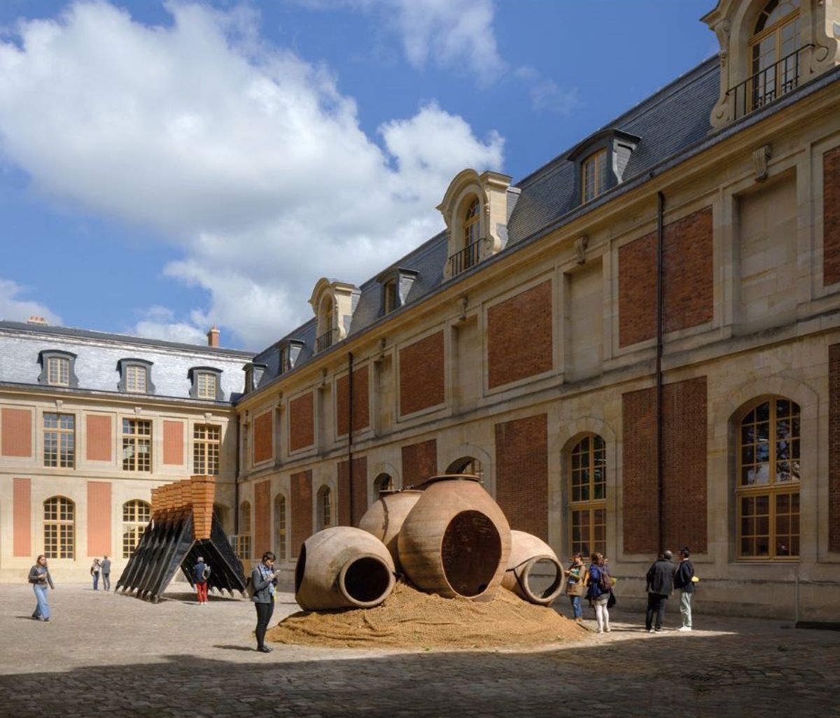 Vue de l’exposition « 4° Celsius entre toi et moi », Bap! Biennale d’architecture et de paysage, Versailles, École nationale supérieure d’architecture, 2025; au premier plan : Andrés Jaque/OFFPOLIN, The Mud Trianon, dolias ; à l’arrière plan : Collective C733, Windcatcher, 6 cheminées solaires. Photo Rafael Gamo