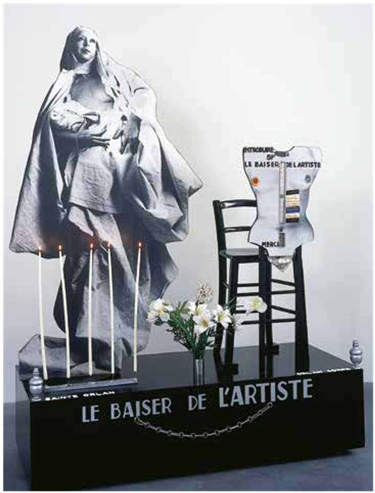 ORLAN, Le Baiser de l’artiste, 1977, tirages contrecollés sur bois, cierges électriques, fleurs artificielles, chaîne métallique, diode clignotante, pièces de métal, bande sonore, Carquefou, Frac des Pays de la Loire. © Stéphane Bellanger
