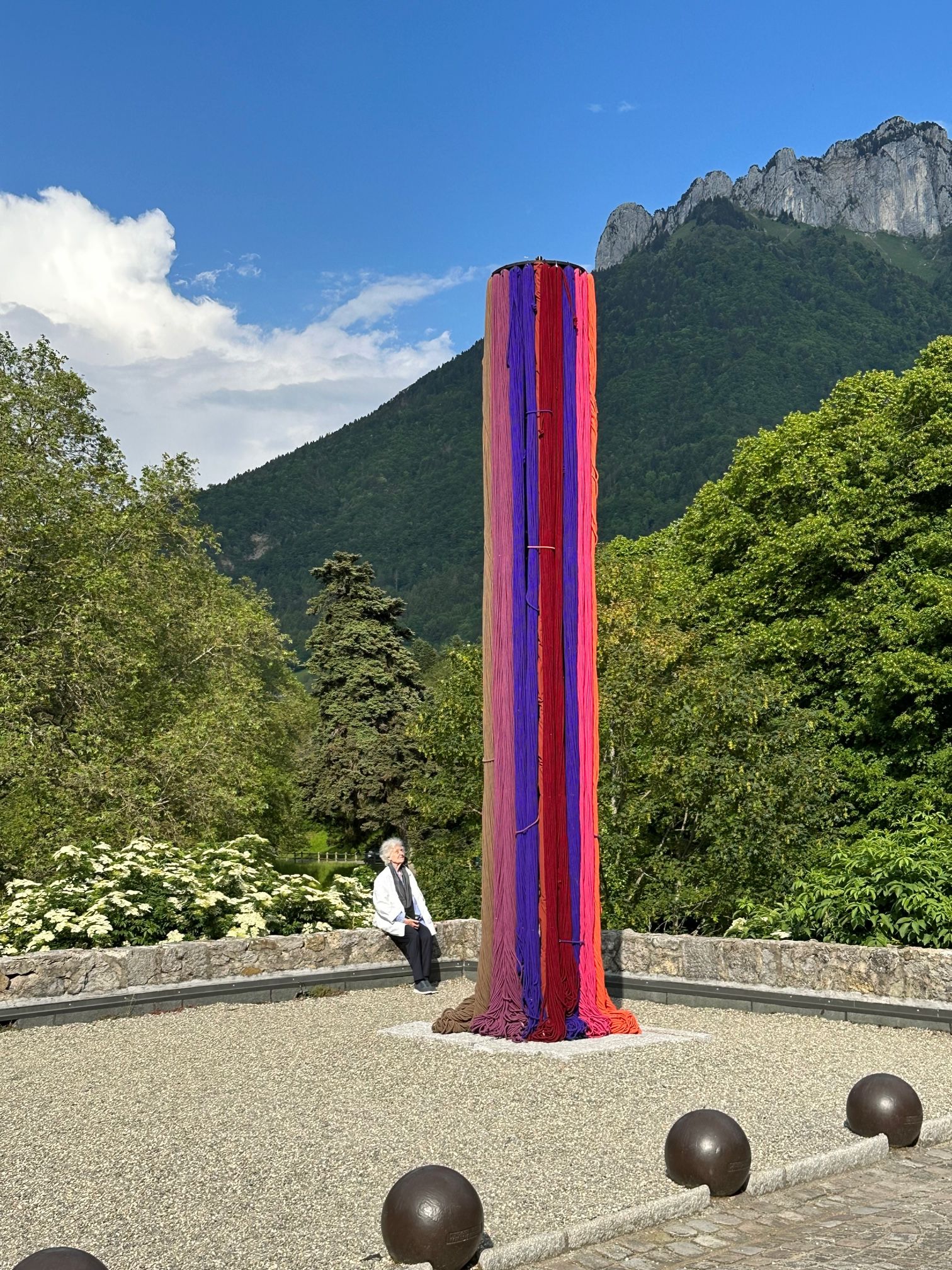 Sheila Hicks devant sa pièce Vers des horizons inconnus au château de Menthon-Saint-Bernard en Haute-Savoie, présentée dans le cadre de l’exposition « Légendes Botaniques ». Photo : Itaka Martignoni