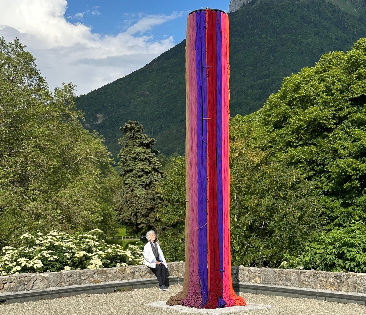 Sheila Hicks devant sa pièce Vers des horizons inconnus au château de Menthon-Saint-Bernard en Haute-Savoie, présentée dans le cadre de l’exposition « Légendes Botaniques ». Photo : Itaka Martignoni