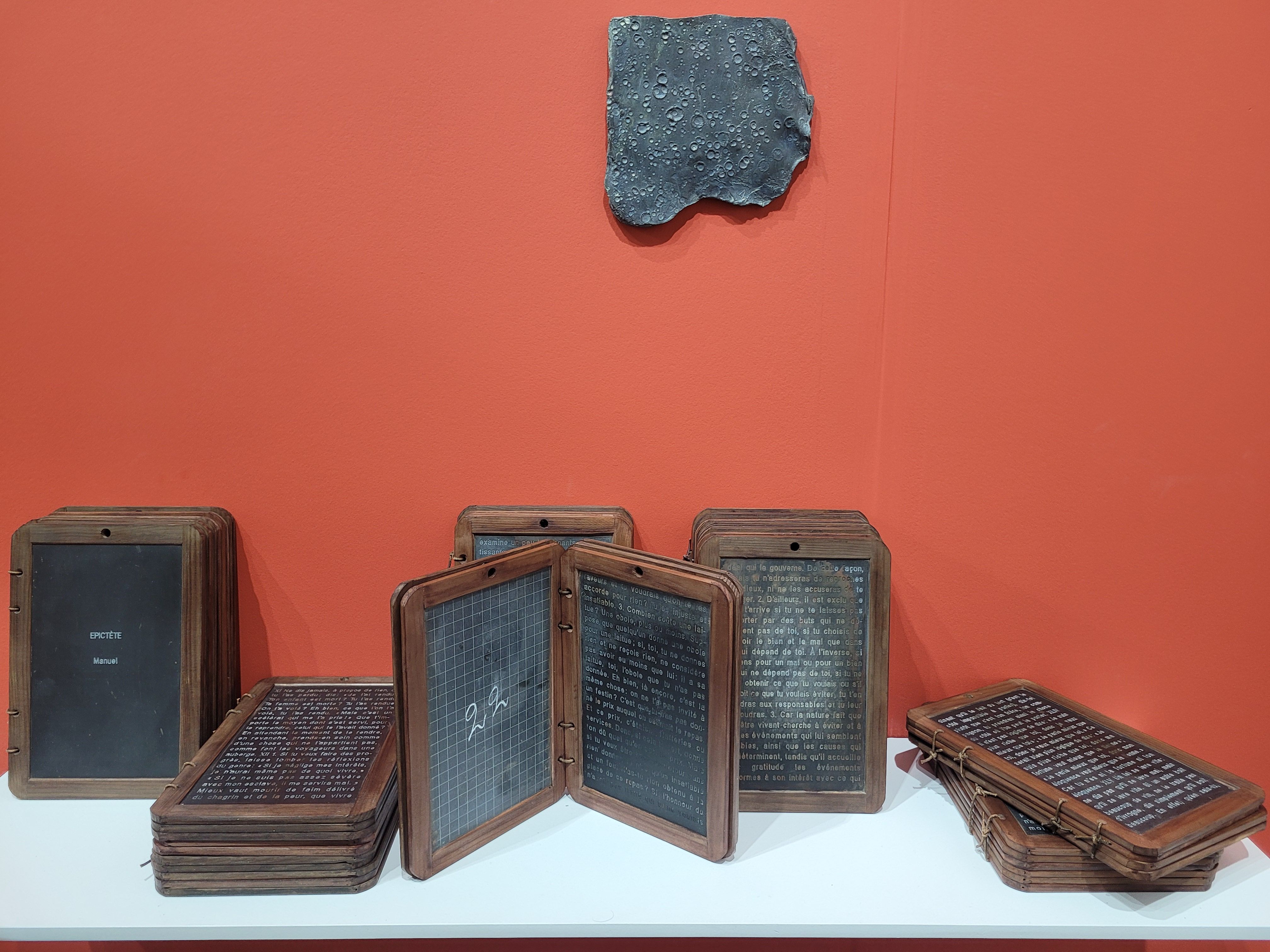 Gabriel Léger, Nul n'est une île (La bibliothèque éternelle) : manuel d'Épictète, 2025, gravure mécanique de l'intégrale du manuel d'Épictète sur 55 tablettes d'ardoises d'écoliers, lanières de cuir. Galerie Sator.

© A.C.