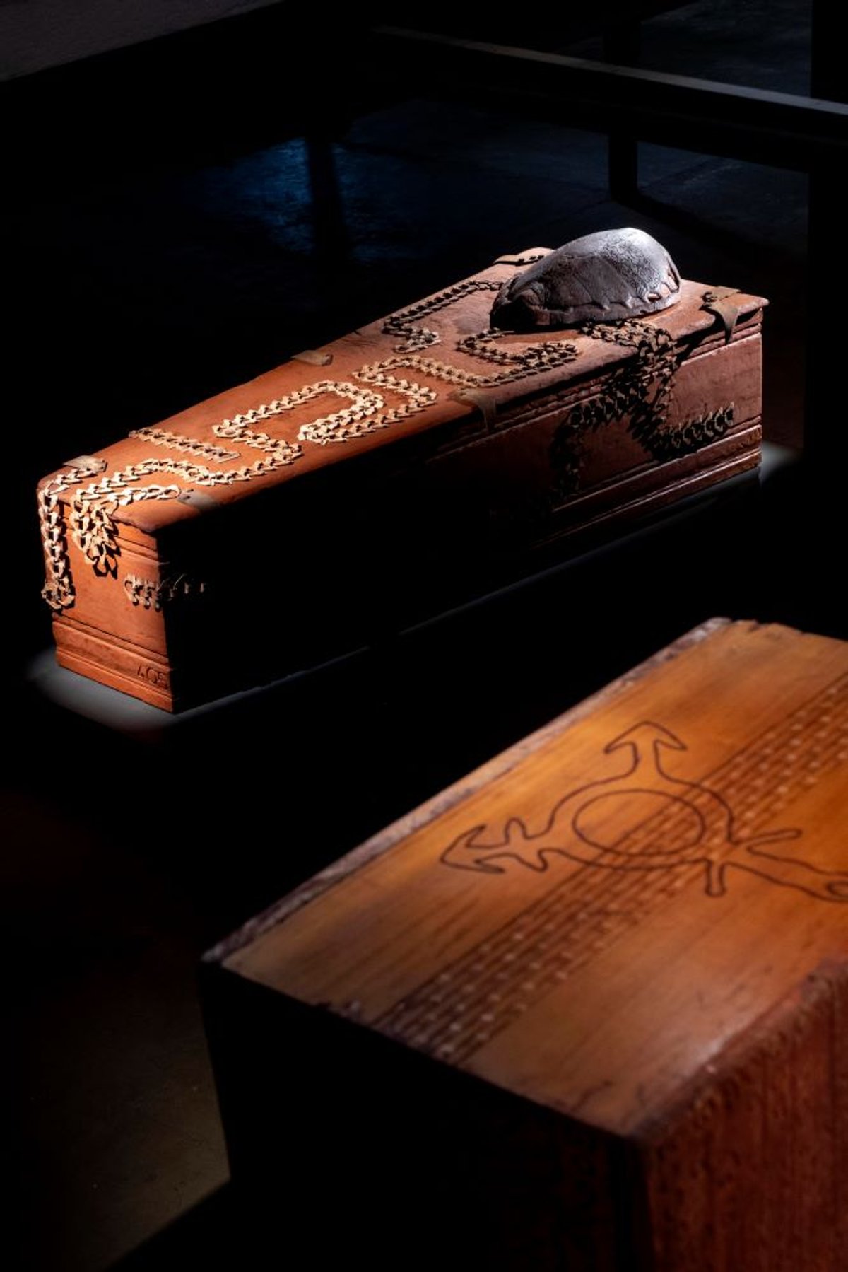 Aïcha Snoussi, Mechanical Transit Box, 2025, cercueil de rapatriement récupéré, gravure sur bois, acier, cuir et encre. © Aïcha Snoussi