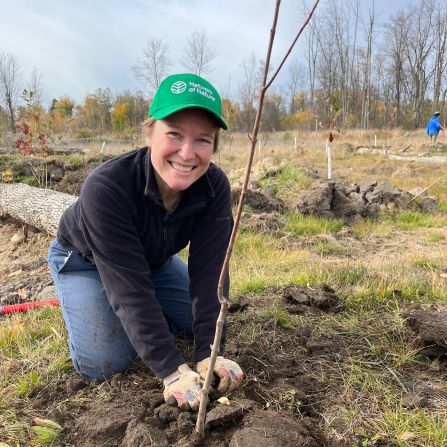 A young woman planting a tree.