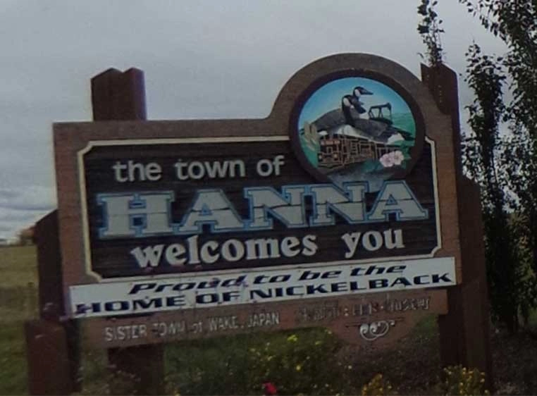 A wooden roadside sign welcoming travelers to the town of Hanna