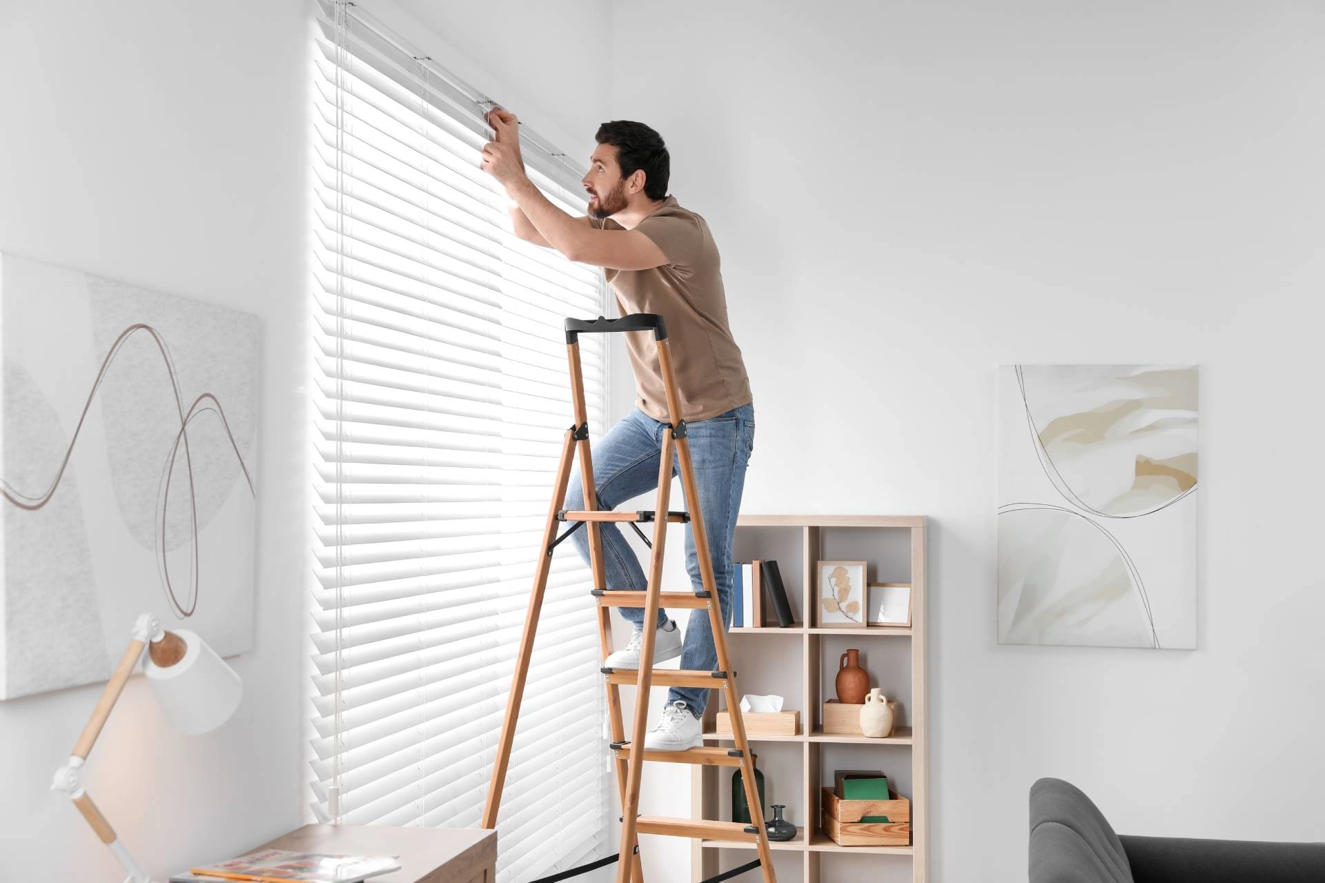 A professional window treatment installer adding outside-mount blinds to a window in a home near Mishawaka, IN