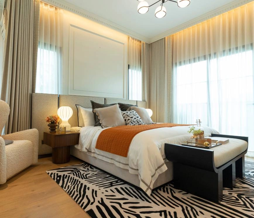 Drapery side panels covering the ends of a large window in a furnished bedroom.