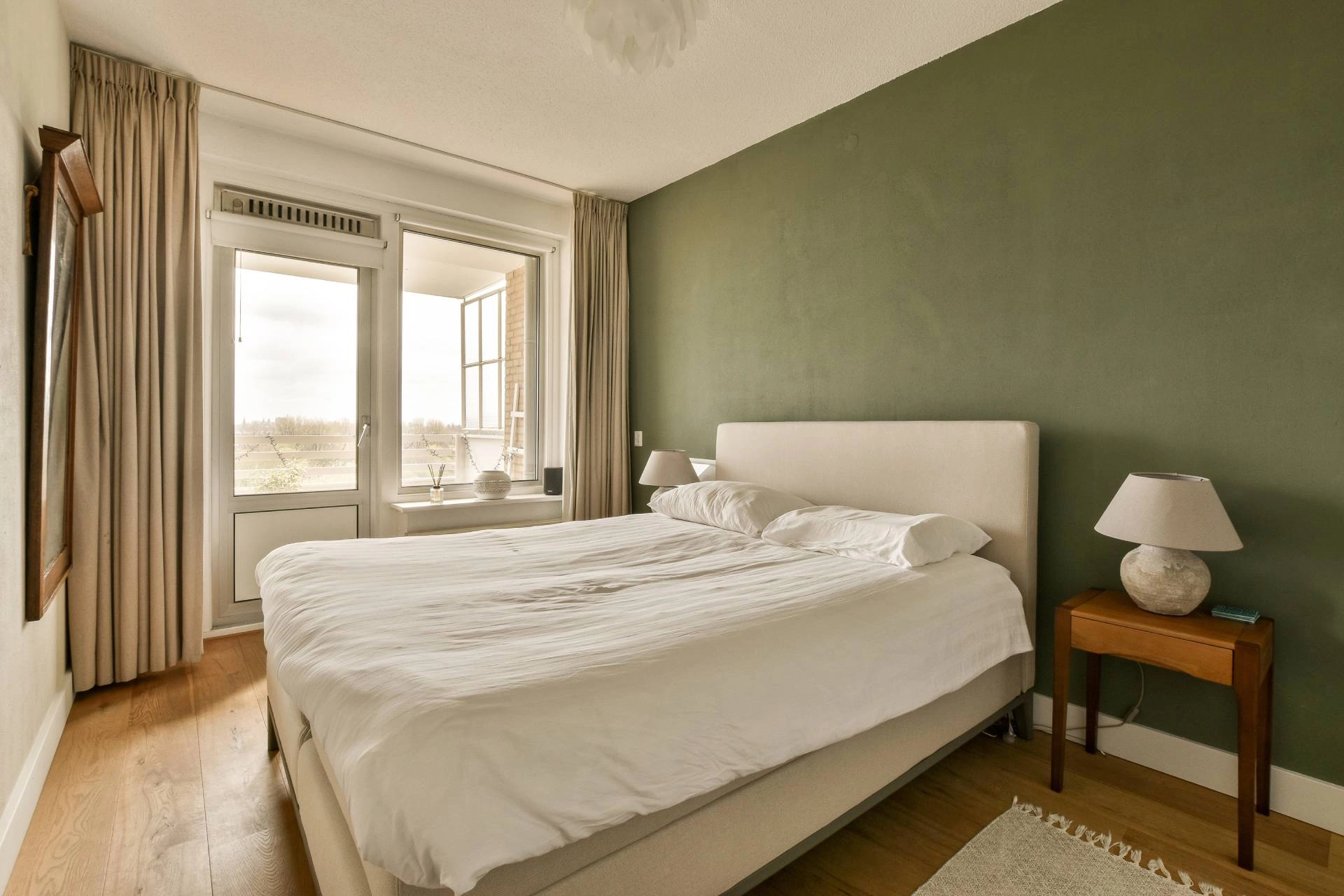 Bedroom with green walls, beige custom drapery, and white roller shades.