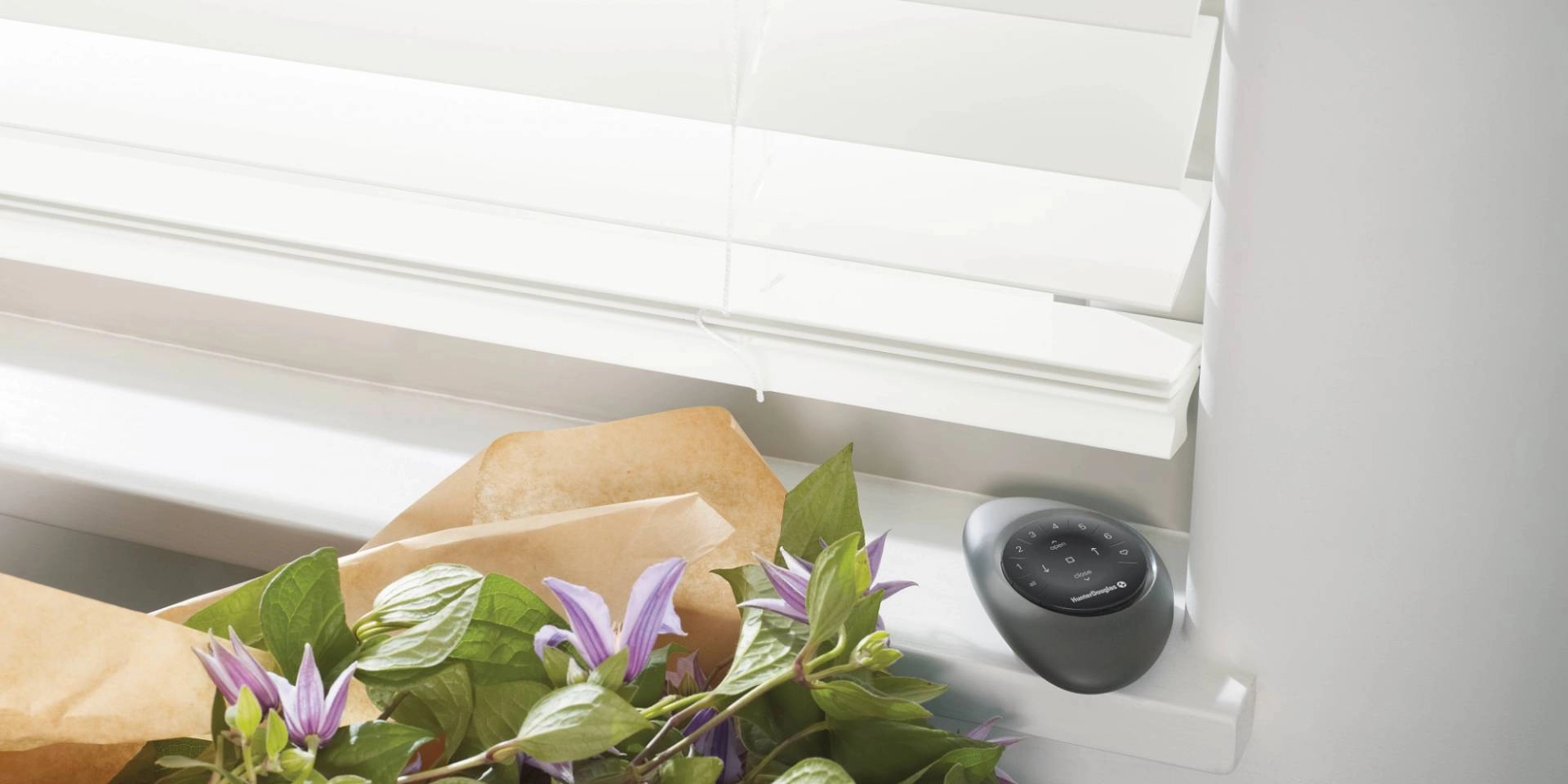 White Hunter Douglas EverWood® Faux Wood Blinds on a window with the PowerView® Automation remote nearby