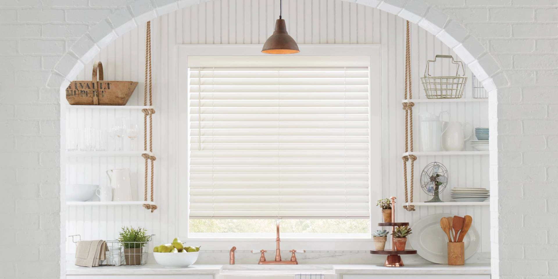 Hunter Douglas Parkland® Wood Blinds on a window above a kitchen sink with a copper faucet