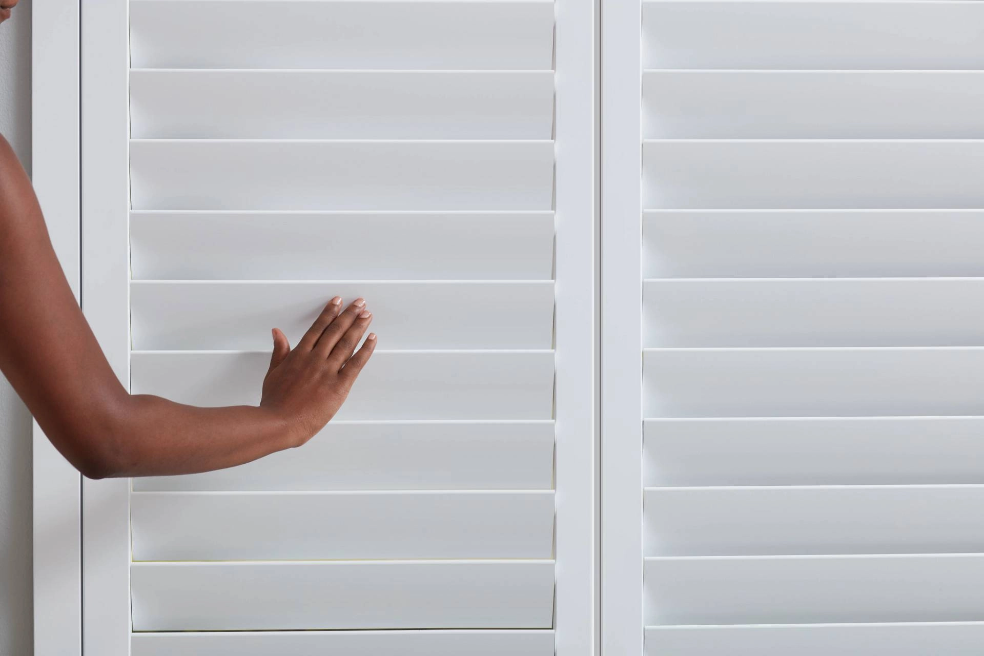 An up-close image of a person's arm closing the louvers of the Hunter Douglas shutters near Jupiter, FL