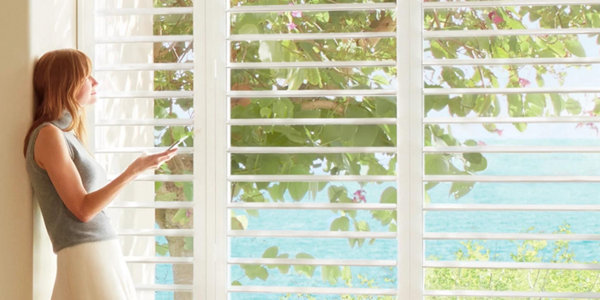 Woman controlling smart home automated window treatment