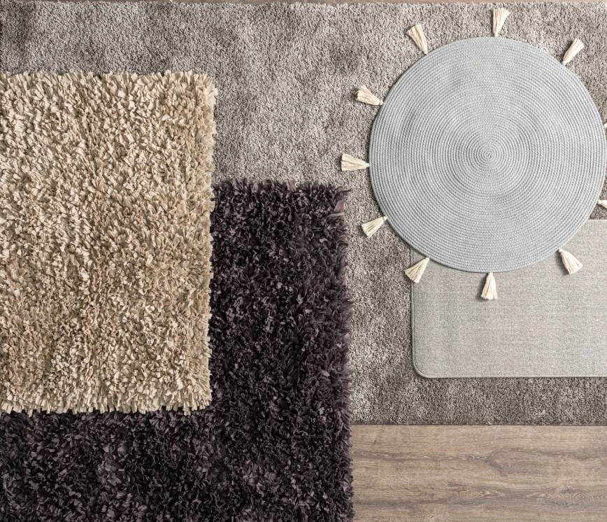 An image of five different area rugs, of various colors and materials, on a dark floor