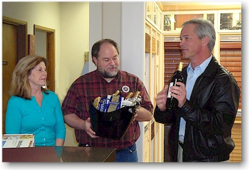 Paul Fergen of Hunter Douglas Northwest presenting a gift of cheese and wine to Kurt and Claudia Evers owners of The Blind Alley to celebrate the 25th Anniversary of The Blind Alley in 2009