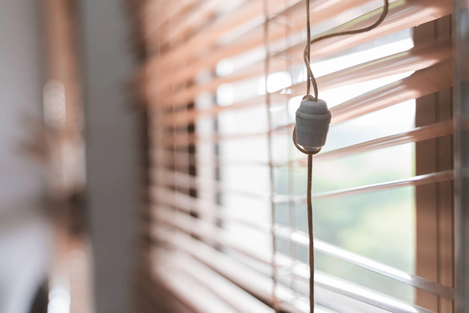 An upclose image of misaligned blinds and a tangled cord in need of repair