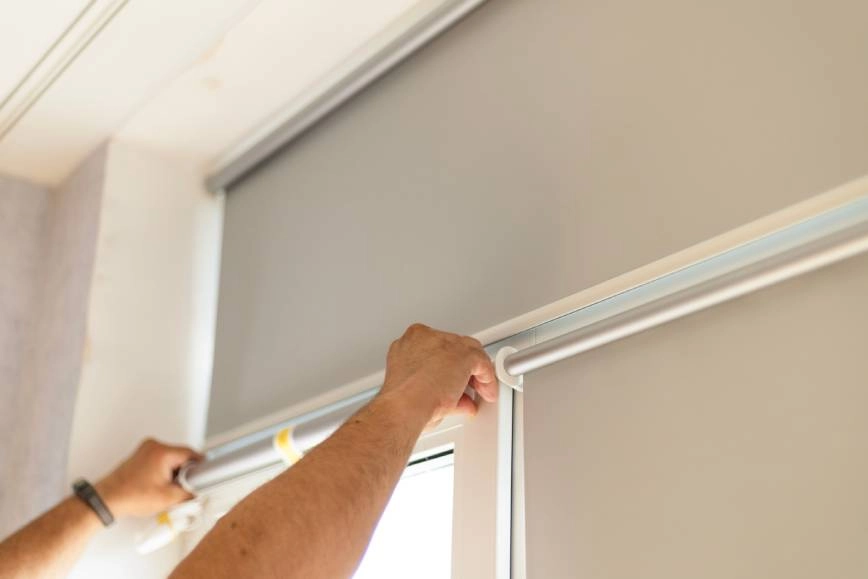 Man repairing a set of window shades.