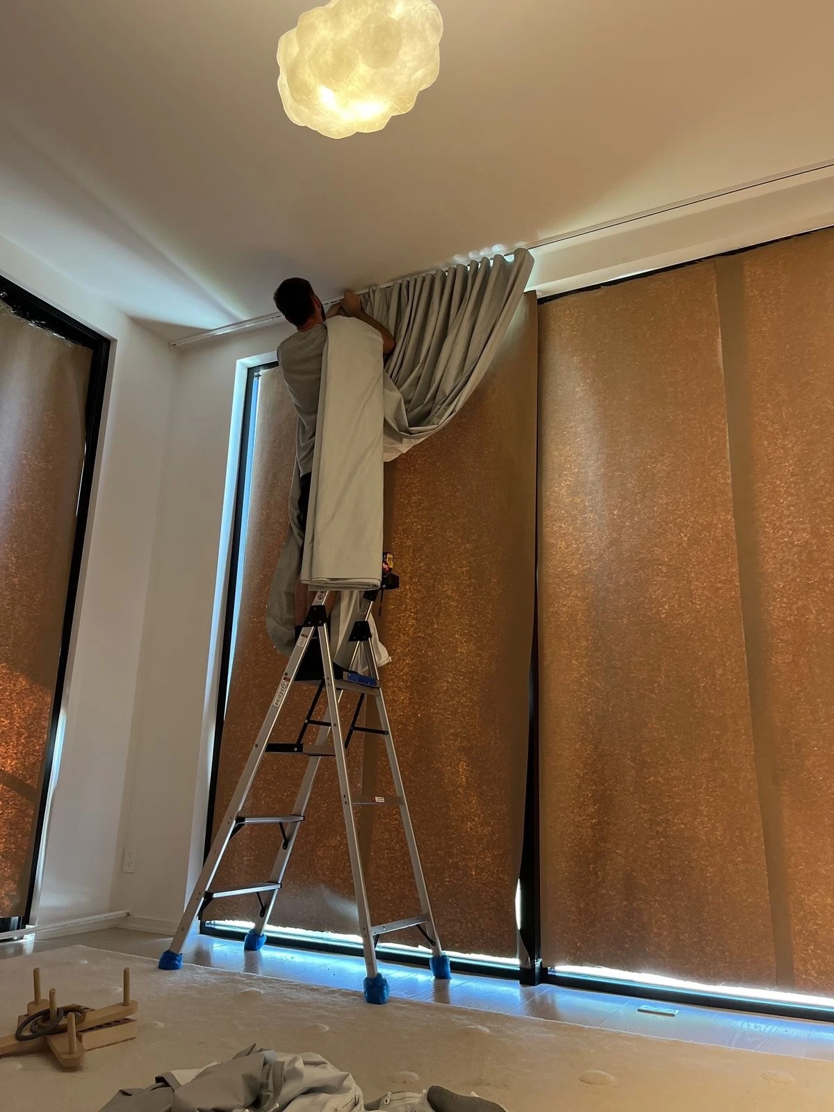 An installer putting drapery in a window