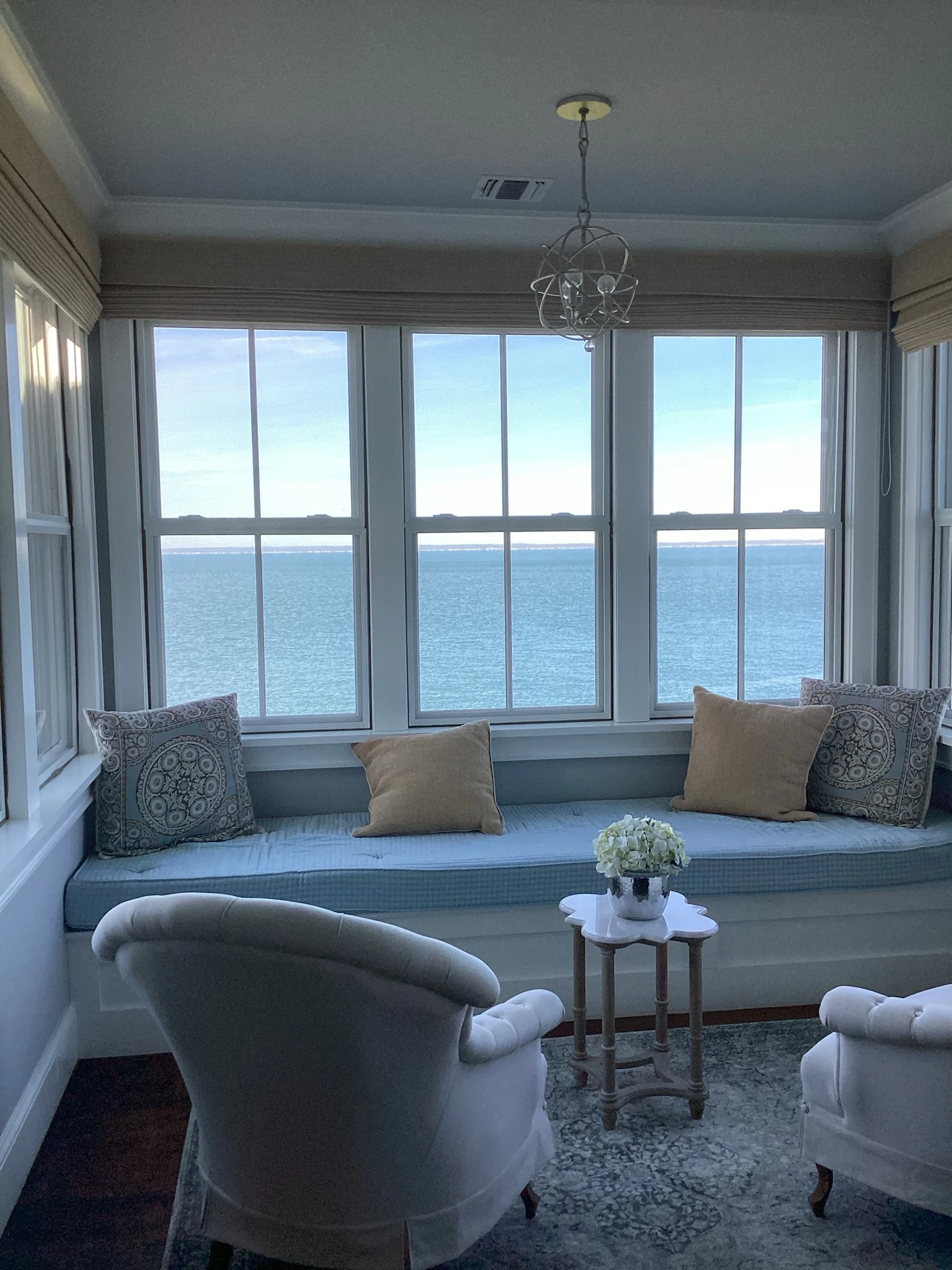 A window seat and windows with shades pulled up.