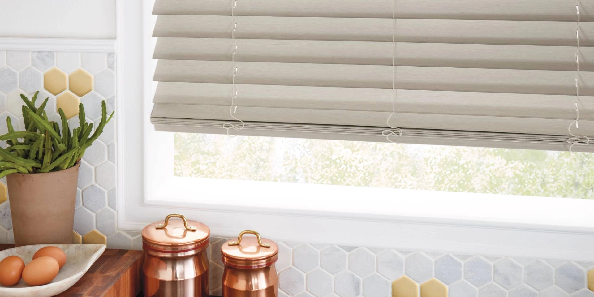 Hunter Douglas EverWood® Faux Wood Blinds on a kitchen window with eggs and decor nearby
