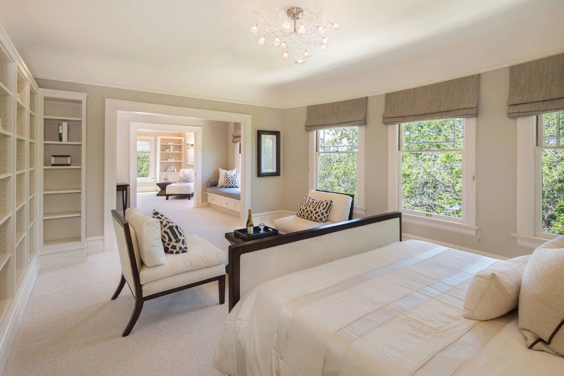 Staged bedroom with accent table, chairs, and custom window shades near Concord, MA