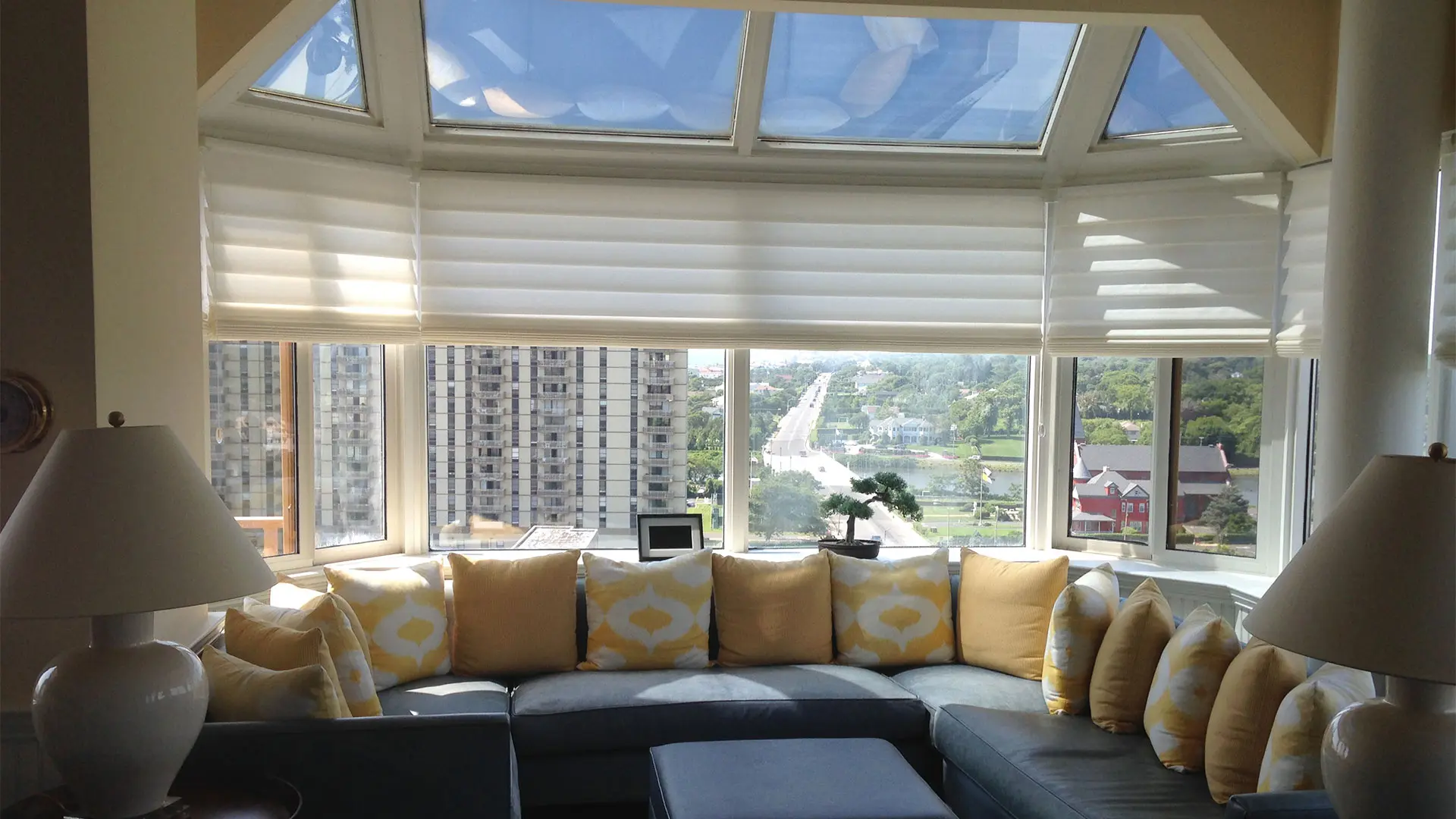 Living room with bay windows featuring Hunter Douglas Vignette shades.