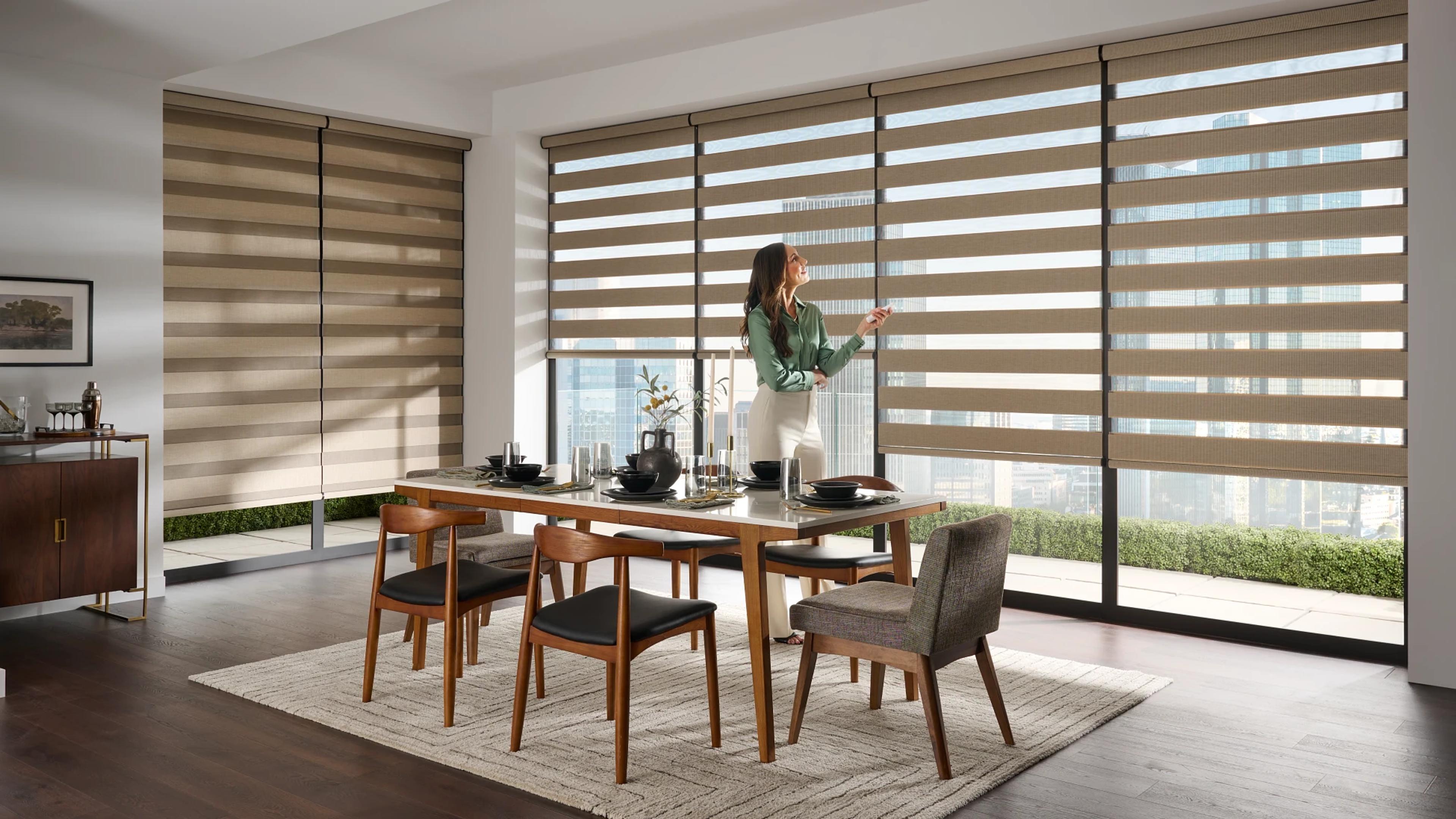 Woman operating automated dual shades in dining room.