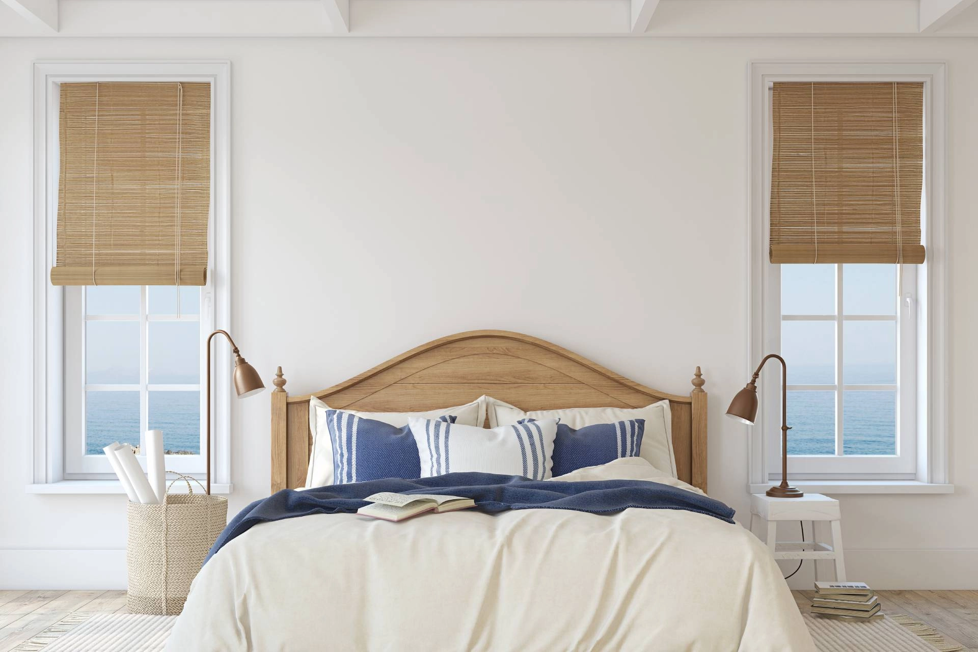 A primary bedroom with a coastal interior design theme, featuring two windows with woven wood shades