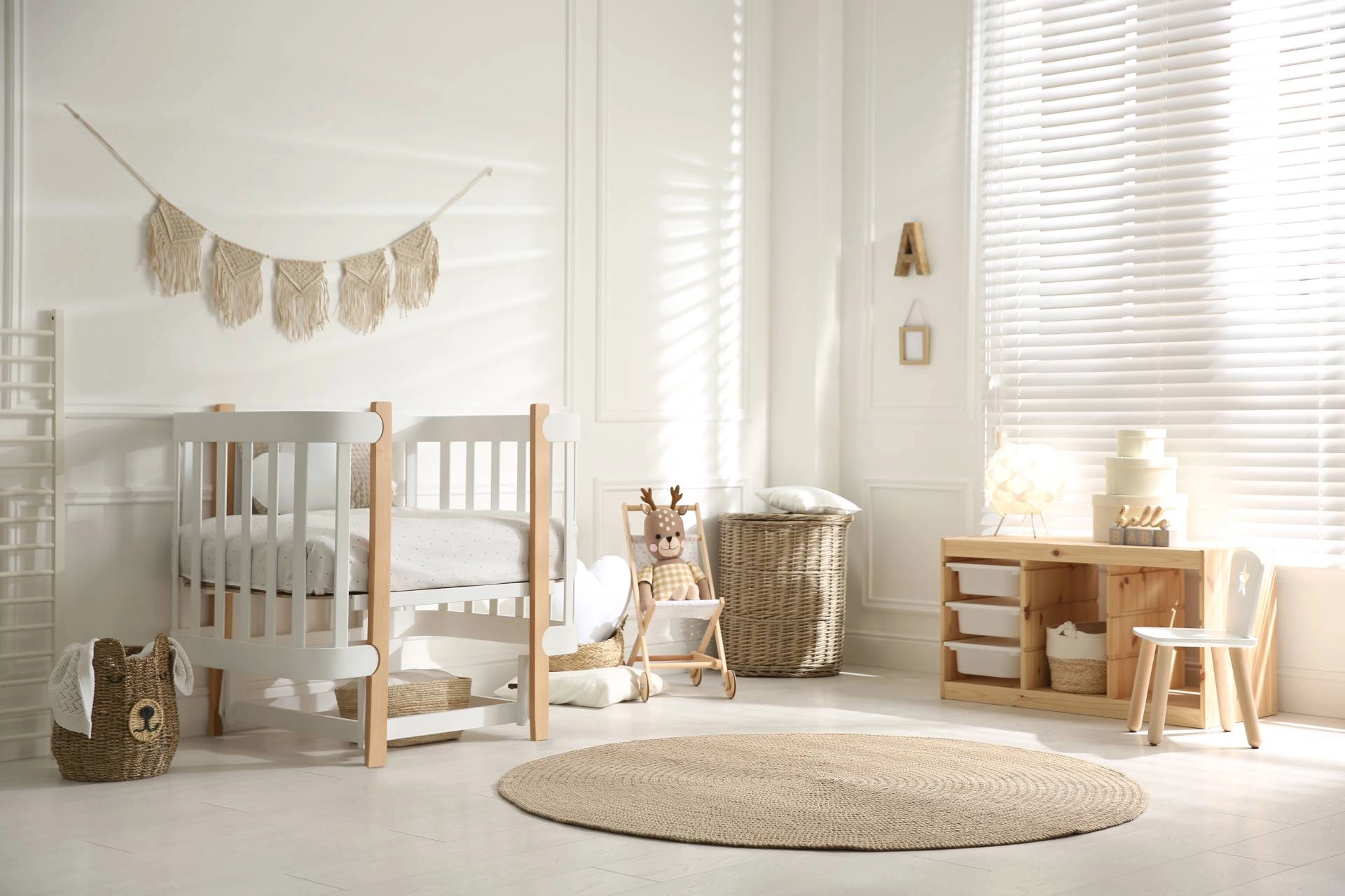 Modern baby's nursery with white and wood furniture and window blinds.