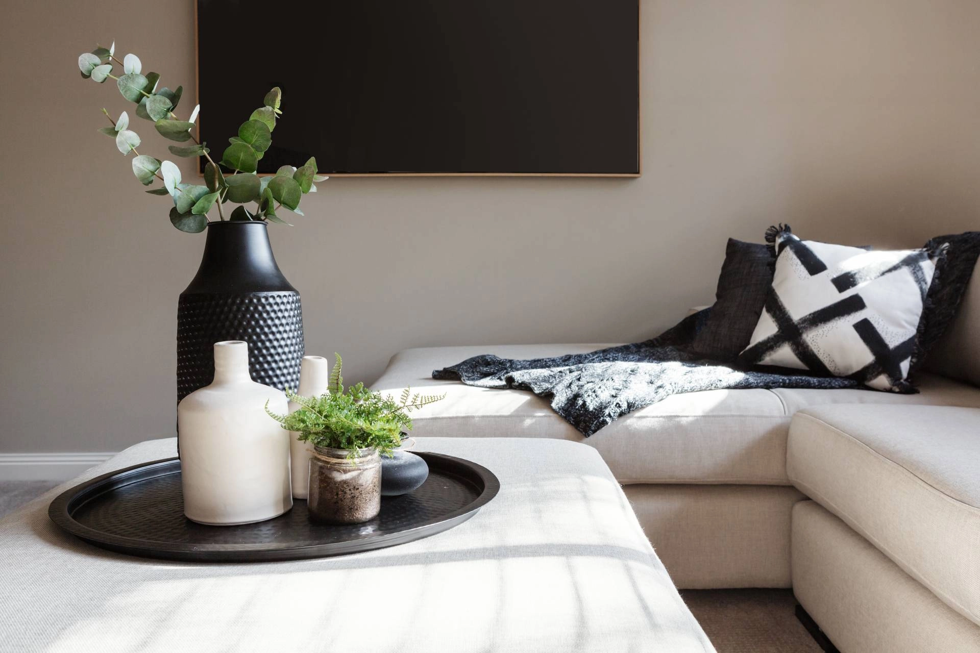 A living room with sleek, black home decor accents, including vases, art, and throw pillows
