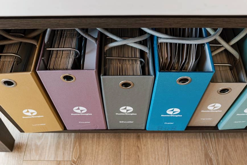 Shelf with six colorful sample binders of Hunter Douglas window treatments at Smart PNW