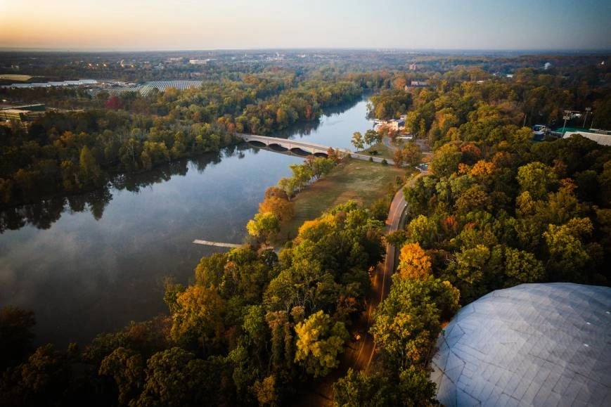An aerial image of Princeton, New Jersey, during an autumn sunrise over a body of water 