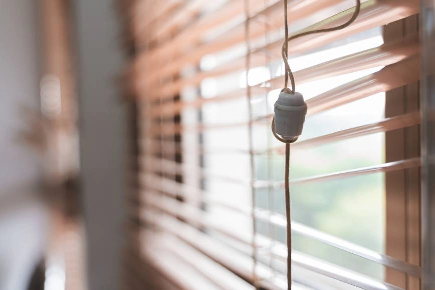 Set of broken blinds with a tangled cord.