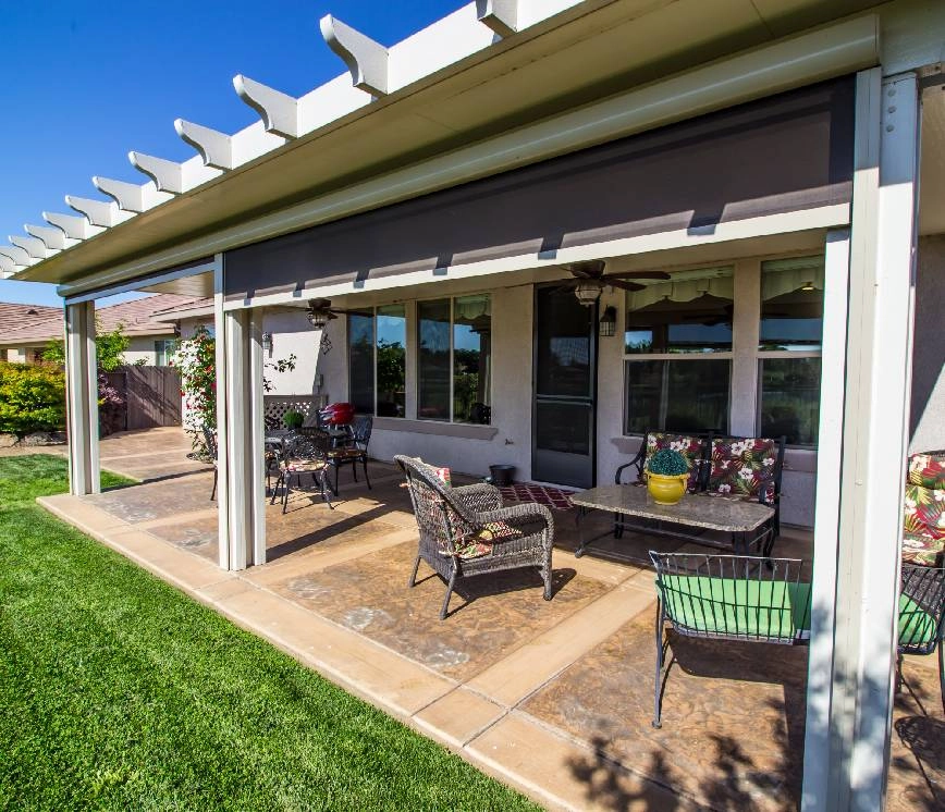 Patio shades providing shade on a covered porch with outdoor furniture.