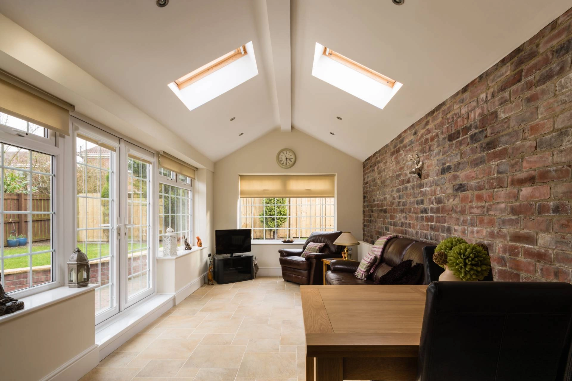 Modern sunroom with furniture, French doors, and sunroom window shades blocking light.