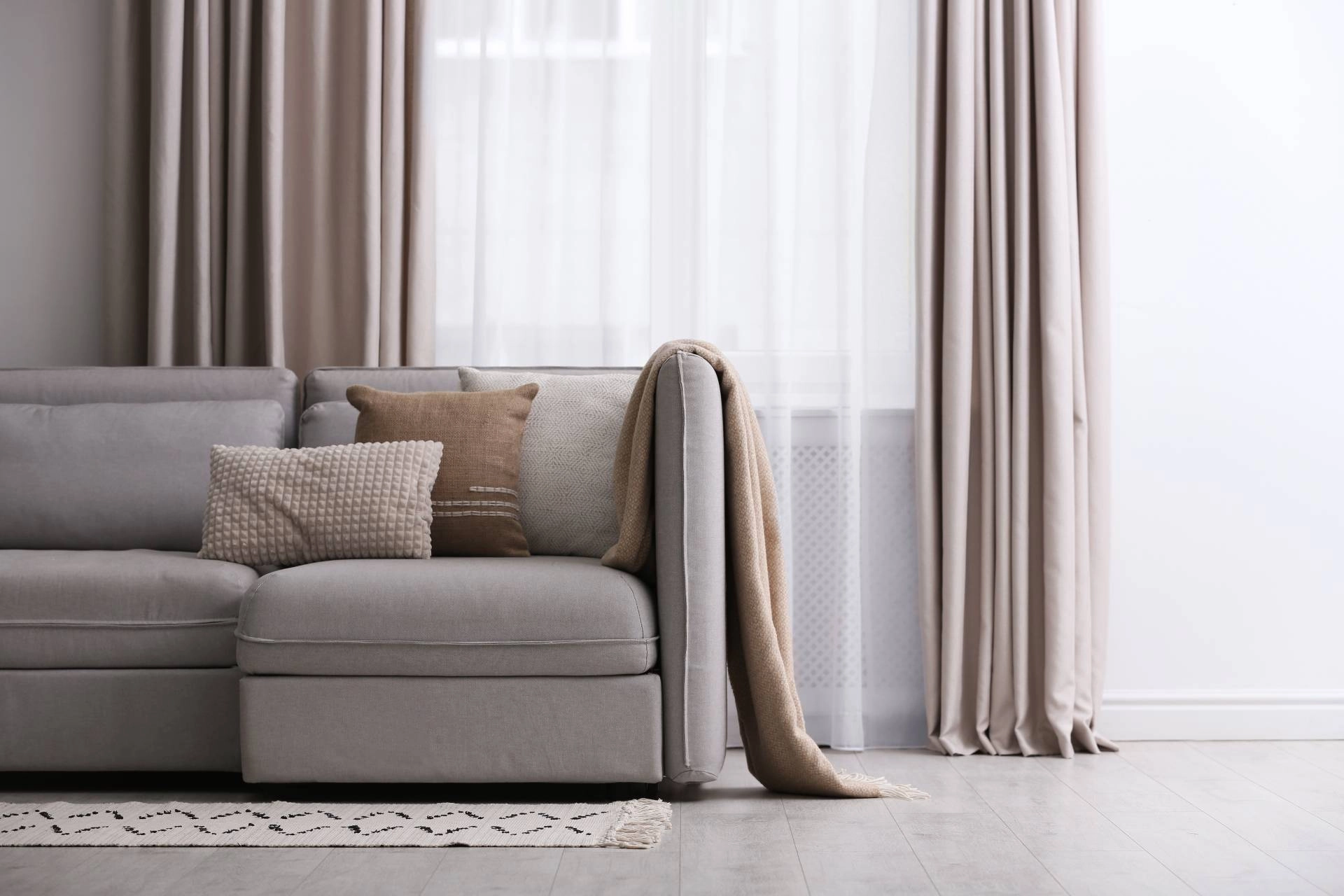 Modern living room with a gray sectional, neutral throw pillows, and custom drapery.